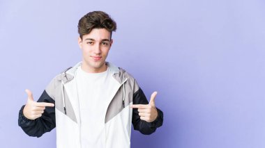 Mor arka planda izole olmuş genç beyaz bir adam gömlek fotokopisini elle gösteriyor, gururlu ve kendinden emin.