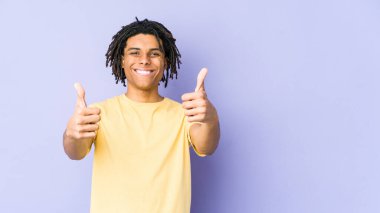 Genç Afrikalı Amerikalı Rasta adam gülümsüyor ve başparmağını kaldırıyor.