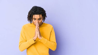 Rasta saç stili giyen genç siyahi adam dua ediyor, bağlılık gösteriyor, dindar biri ilahi ilham arıyor..