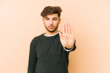 Bej bir arka planda izole edilmiş genç bir Arap adam elini uzatmış, dur işareti göstererek seni engelliyor..