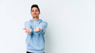 Beyaz arka planda izole edilmiş genç beyaz bir adam dudaklarını katlıyor ve hava öpücüğü vermek için avuç içleri tutuyor..