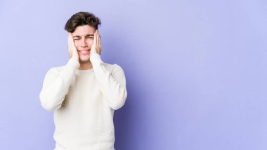 Mor arka planda izole edilmiş genç beyaz bir adam ağlıyor, bir şeyden memnun değil, acı ve kafa karışıklığı konsepti..