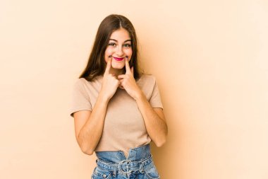 Beyazlı genç bir kadın, iki seçenek arasında kuşkuyla bej arka planda izole edilmiş..