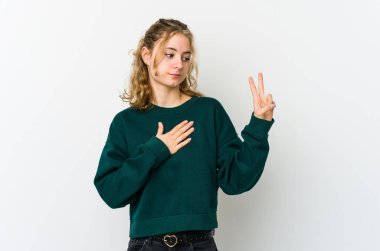 Beyaz arka planda genç beyaz kadın yemin ediyor, elini göğsüne koyuyor..