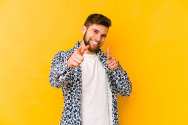 Sarı arka planda izole edilmiş genç beyaz adam öne bakan neşeli gülücükler.