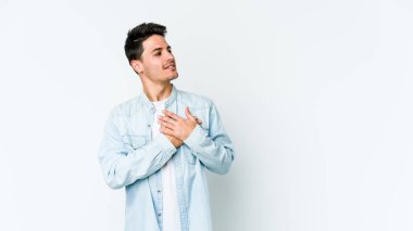 Beyaz arka planda izole edilmiş beyaz tenli genç bir adam, dostane bir ifadeye sahip, avuçlarını göğsüne bastırıyor. Aşk konsepti.