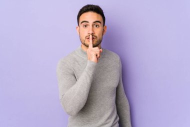 Mor arka planda izole edilmiş genç beyaz bir adam bir sır saklıyor ya da sessizlik istiyor..