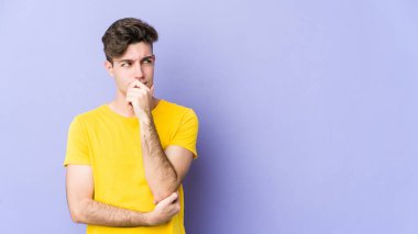 Mor arka planda izole edilmiş genç beyaz adam rahatlamış bir şeyin fotokopi odasına baktığını düşünüyor..