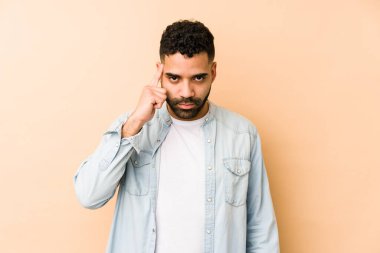 Genç, melez Arap bir adam, tapınağı parmağıyla göstererek, düşünerek, bir göreve odaklanmış..