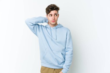 Beyaz arka planda izole edilmiş genç beyaz bir adam kafasının arkasına dokunuyor, düşünüyor ve bir seçim yapıyor..