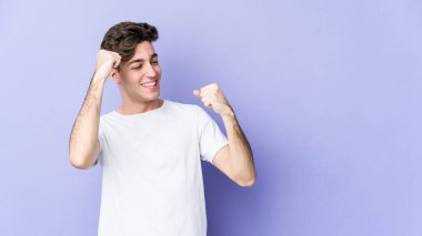 Mor arka planda izole edilmiş genç beyaz adam zafer kazandıktan sonra yumruğunu kaldırıyor, kazanan konsept..