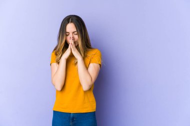 Mor arka planda izole edilmiş genç beyaz kadın dua ediyor, bağlılık gösteriyor, dindar biri ilahi ilham arıyor..