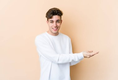 Beyaz tenli genç, bej arka planda izole edilmiş. Elinde palmiye ağacında bir fotokopi alanı var..