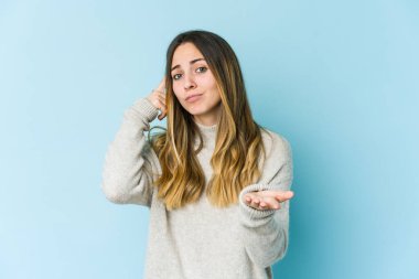 Beyaz bir kadın mavi arka planda izole edilmiş ve elinde bir ürün tutuyor..