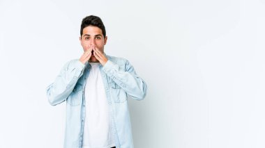 Beyaz arka planda izole edilmiş genç beyaz adam elleriyle ağzını kapatırken şok oldu..