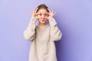 Mor arka planda genç beyaz bir kadın bir başarı fırsatı bulmak için gözlerini açık tutuyor..