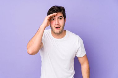 Mor arka planda izole genç adam yüksek sesle bağırıyor, gözleri açık ve elleri gergin tutuyor..