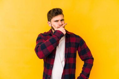 Kafkasyalı genç bir adam sarı arka planda izole edilmiş. Bir strateji planlıyor, bir iş yolu düşünüyor..