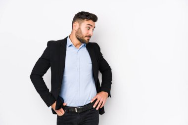 Beyaz arka planda beyaz tenli genç beyaz bir iş adamı. Kafasının arkasına dokunuyor, düşünüyor ve bir seçim yapıyor..
