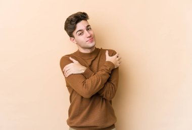 Beyaz tenli genç adam bej arka planda izole edilmiş, gülümsüyor ve mutlu..