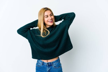 Genç sarışın kadın, beyaz arka planda izole edilmiş. Kendinden emin, elleri başının arkasında..