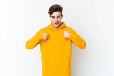 Beyaz arka planda izole edilmiş genç beyaz bir adam parmağını göstererek şaşırdı, geniş bir gülümsemeyle..