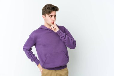 Beyaz arka planda izole edilmiş genç beyaz bir adam ya sır saklıyor ya da sessizlik istiyor..