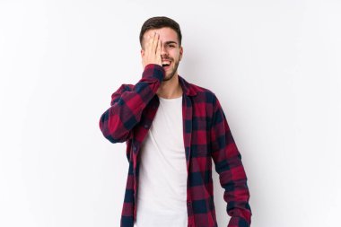 Beyaz arka planda poz veren beyaz bir genç, yüzünün yarısını palmiye ile örterek eğleniyor..