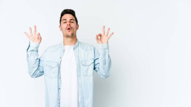 Beyaz arka planda izole edilmiş genç beyaz adam yoğun bir günün ardından rahatlıyor. Yoga yapıyor..