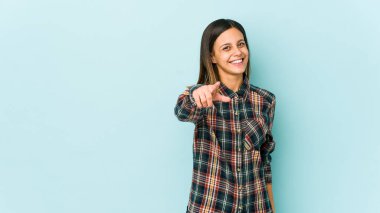 Mavi arka planda soyutlanmış genç bir kadın. Neşeli gülücükler öne bakıyor..