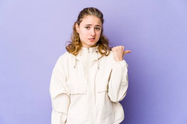 Mor arka planda beyaz bir kadın işaret parmağıyla bir fotokopi alanını işaret ederek şok oldu..