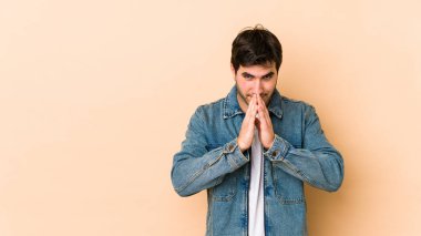 Genç adam bej rengi arka planda izole edildi. Aklında bir plan oluşturdu, bir fikir oluşturdu..