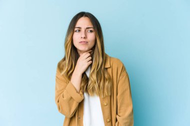 Mavi arka planda izole edilmiş genç beyaz kadın virüs ya da enfeksiyon yüzünden boğazında ağrı hissediyor..