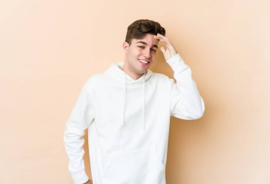 Beyazlı genç bir adam bej arka planda izole edilmiş neşeli bir şekilde gülüyor. Mutluluk kavramı.