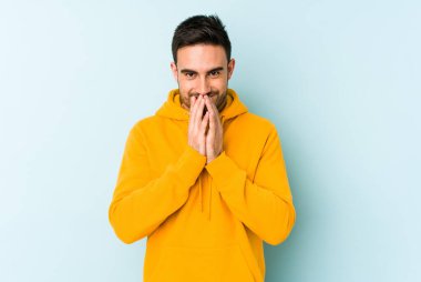 Kafkasyalı genç bir adam mavi arka planda izole edildi. Aklında bir plan kuruyor, bir fikir kuruyor..