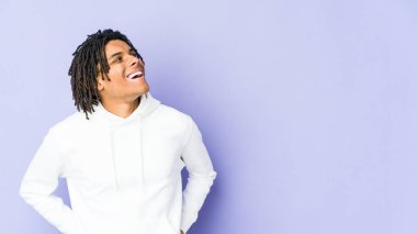 Genç Afrikalı Amerikalı Rasta adam gevşemiş ve mutlu bir şekilde gülüyor, boynunda dişlerini gösteriyor..