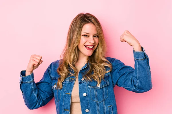 Pembe arka planda soyutlanmış, tasasız ve heyecanlı genç bir beyaz kadın. Zafer konsepti.