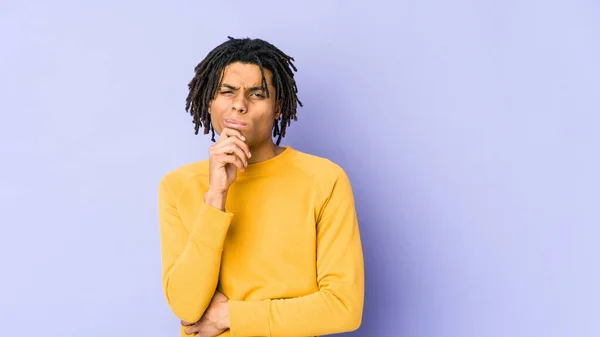 Young black man wearing rasta hairstyle thinking and looking up, being reflective, contemplating, having a fantasy.