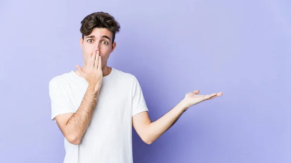 Jovem Caucasiano Isolado Fundo Roxo Impressionado Segurando Espaço Cópia Palma — Fotografia de Stock