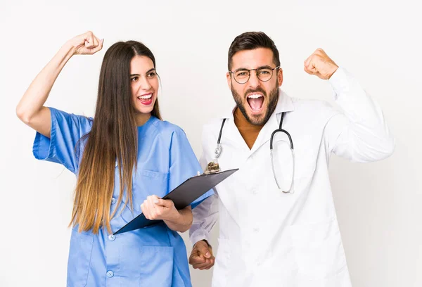 Young doctor man and a nurse isolated raising fist after a victory, winner concept.