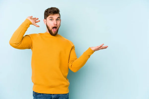 Young Caucasian Man Isolated Blue Background Holds Copy Space Palm — Stock Photo, Image