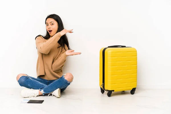 若いです中国の旅行者女性座っています上の床にスーツケースとともに隔離されたショックと驚きを持っていますコピースペース間手 — ストック写真