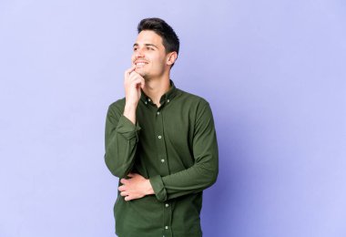 Mor arka planda izole edilmiş genç beyaz adam rahatlamış bir şeyin fotokopi odasına baktığını düşünüyor..