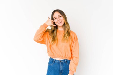 Beyaz arka planda izole edilmiş genç beyaz kadın parmaklarıyla bir cep telefonu hareketi gösteriyor..