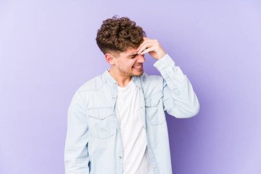 Sarışın, kıvırcık saçlı, beyaz tenli bir adam bir şeyi unutuyor. Alnına avuç içi ve gözlerini kapatıyor..