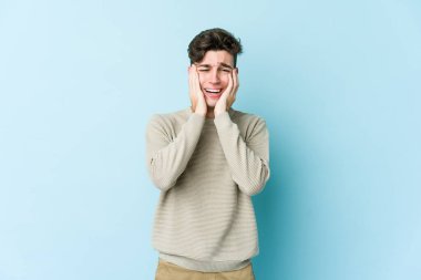 Kafkasyalı genç adam mavi arka planda izole edilmiş sızlanıyor ve ağlıyordu..