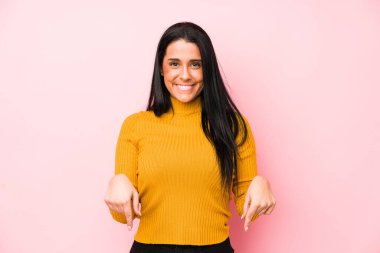 Pembe arka planda izole edilmiş genç beyaz kadın parmakları aşağıda, olumlu bir his var..