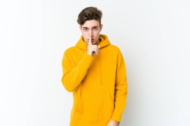 Beyaz arka planda izole edilmiş genç beyaz bir adam ya sır saklıyor ya da sessizlik istiyor..