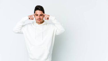 Beyaz arka planda izole edilmiş genç beyaz bir adam bir göreve odaklanmış, işaret parmaklarını işaret ediyor..