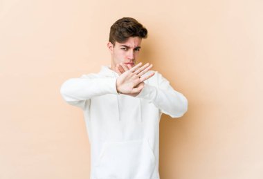 Beyazlı genç bir adam bej arka planda izole edilmiş, inkar jesti yapıyor.
